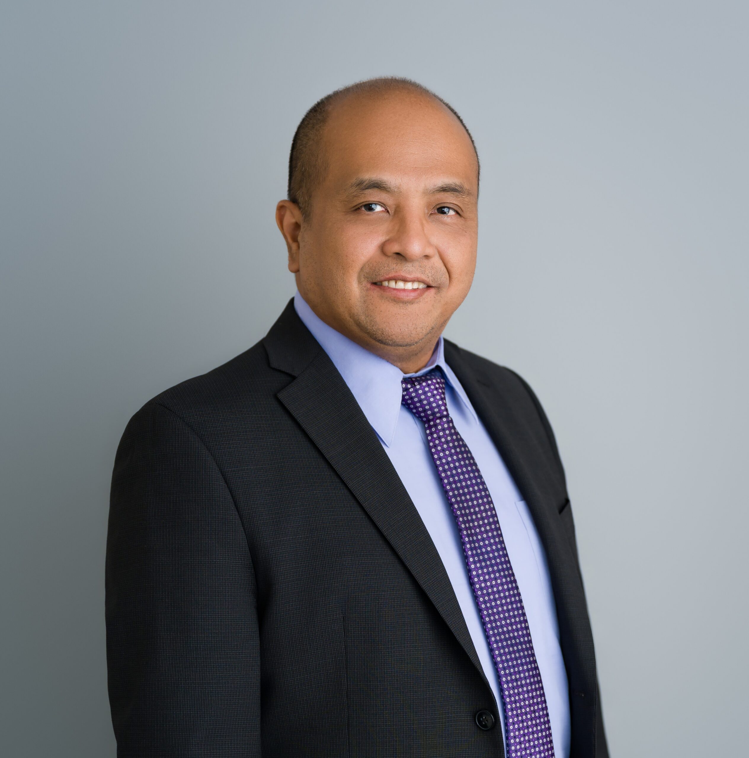 a gentleman wearing a dark suit jacket and a lighter color shirt with a tie